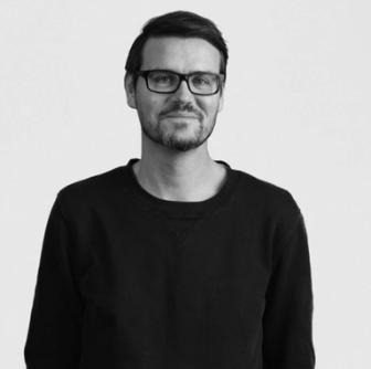 Thomas Hartwig, looks out towards camera smiling.