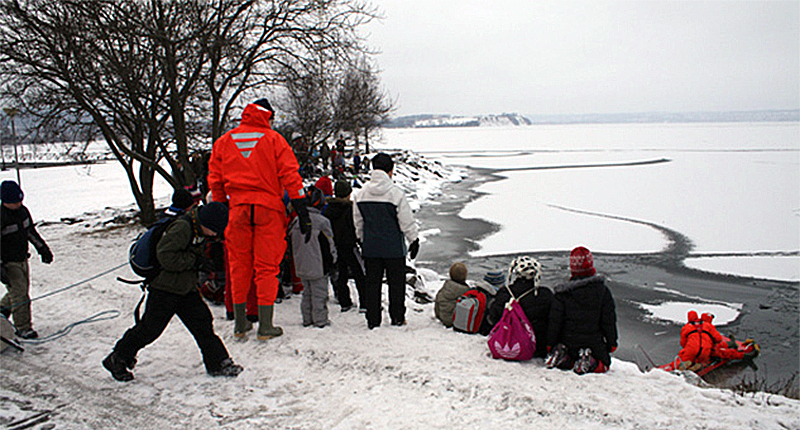 Personer står runt en isig sjö
